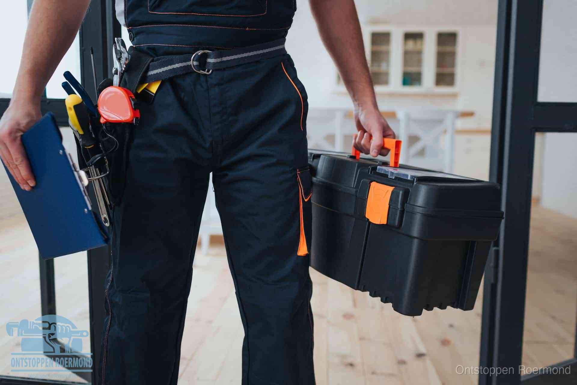 Een monteur met gereedschapsriem en klembord in een keuken, klaar om een transparante prijs voor het gootsteen ontstoppen in Roermond te geven