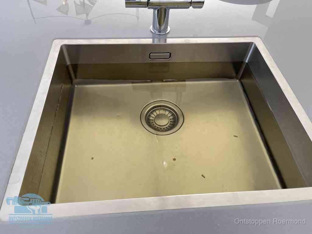 Stilstaand water in een rvs spoelbak dat niet wegloopt, een duidelijk signaal van een gootsteenverstopping in Roermond
