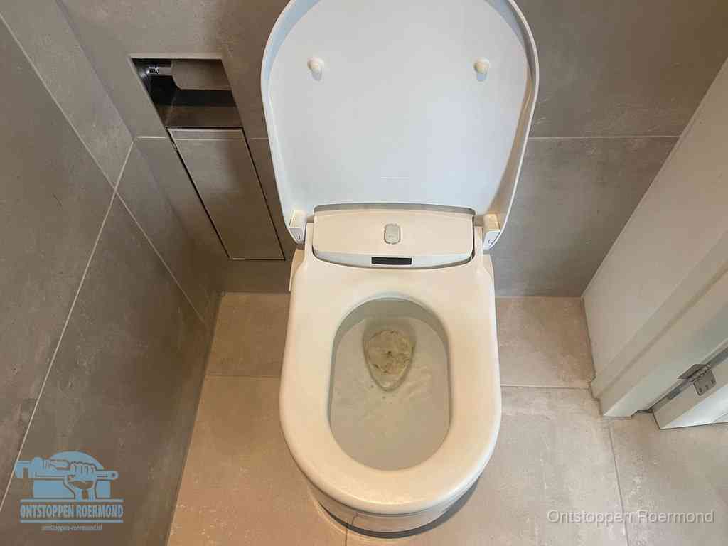 Een wit hangtoilet waarin een prop wc-papier op het water blijft drijven, een duidelijk signaal van een verstopte wc in Roermond