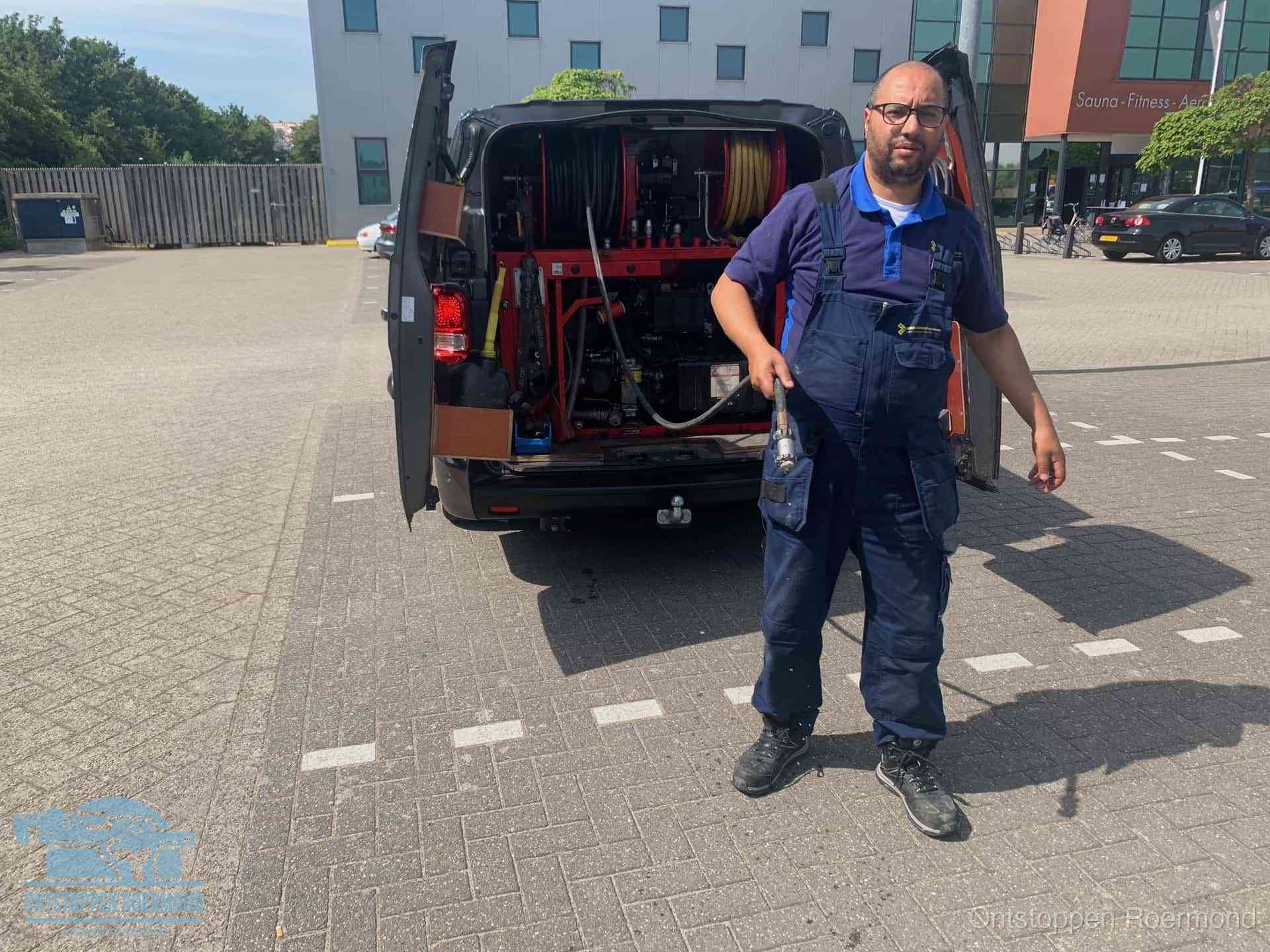 Een monteur bij zijn bestelbus met een hogedruk- en rioolreinigingsunit, klaar om de oorzaak van terugkerende wc-verstoppingen aan te pakken in Roermond