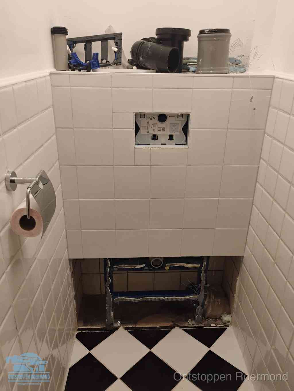 Een toiletruimte waar het hangtoilet en de inbouwreservoir-onderdelen zijn vrijgelegd voor onderhoud, periodiek nazicht voorkomt een wc-verstopping in Roermond