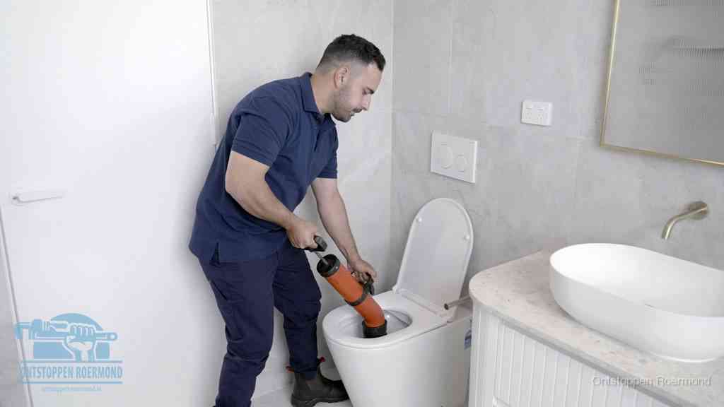 Een monteur gebruikt een handmatige perspomp (toiletontstopper) op een wandcloset tijdens het professioneel wc ontstoppen in Roermond